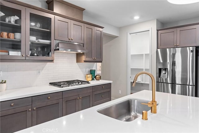 kitchen featuring stainless steel appliances, under cabinet range hood, a sink, light countertops, and recessed lighting