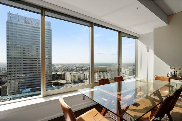 dining space featuring a city view, a wall of windows, and wood finished floors