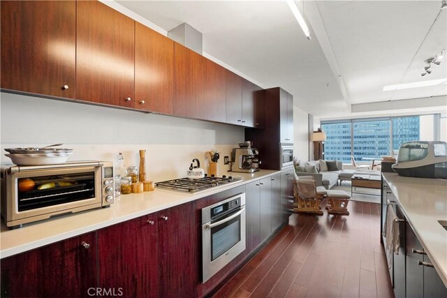 kitchen with a toaster, open floor plan, dark wood finished floors, light countertops, and appliances with stainless steel finishes