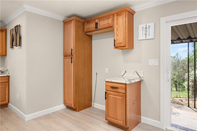 kitchen featuring baseboards, ornamental molding, light countertops, light wood-style floors, and brown cabinetry