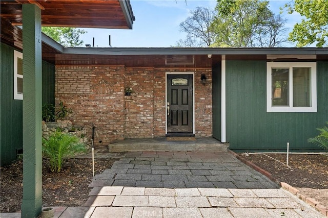 view of exterior entry with brick siding