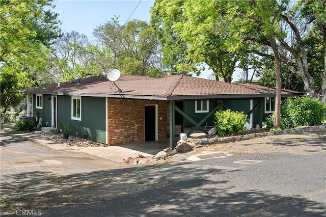 ranch-style home featuring brick siding, an attached carport, and driveway