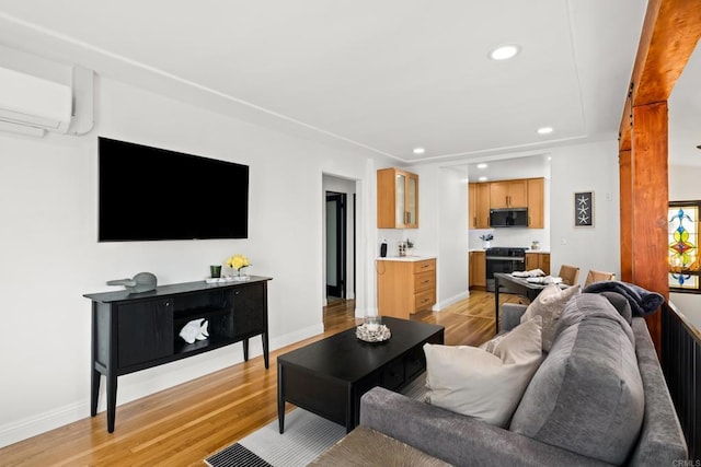 living area with an AC wall unit, light wood finished floors, recessed lighting, and baseboards