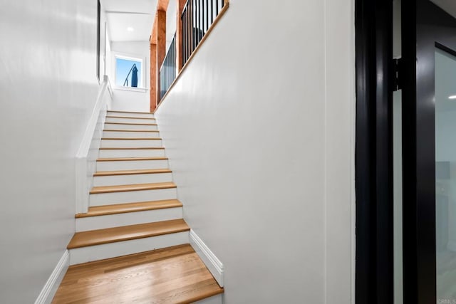 staircase with baseboards and wood finished floors