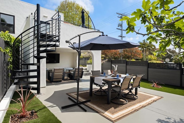 view of patio / terrace featuring outdoor dining space, fence, and stairway