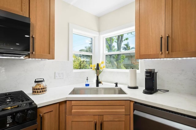 kitchen featuring dishwasher, a sink, black gas range, light countertops, and decorative backsplash