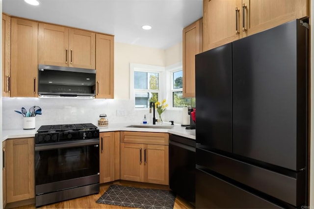 kitchen with black appliances, a sink, light countertops, decorative backsplash, and recessed lighting