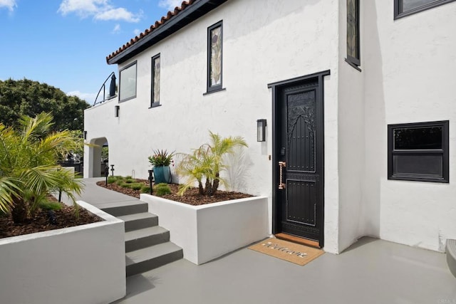 view of exterior entry featuring stucco siding and a tile roof