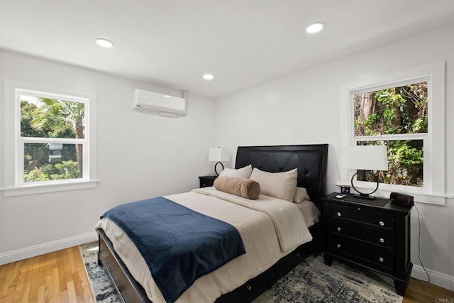 bedroom with a wall unit AC, multiple windows, wood finished floors, and recessed lighting
