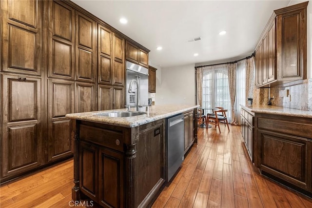 kitchen with a kitchen island with sink, appliances with stainless steel finishes, visible vents, and light wood-type flooring