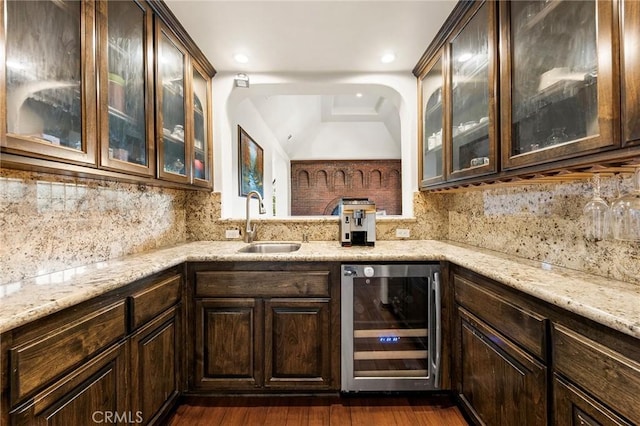 bar featuring beverage cooler, dark wood finished floors, a sink, and tasteful backsplash