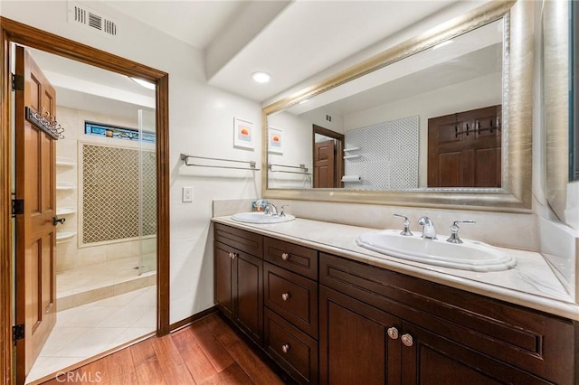 full bath featuring visible vents, a sink, double vanity, and a shower stall