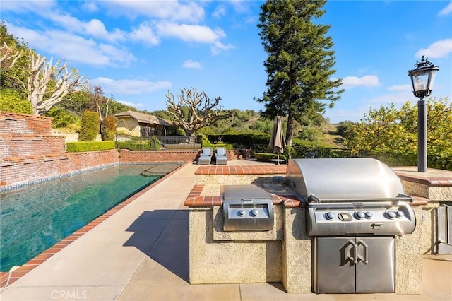 view of patio with exterior kitchen, area for grilling, and an outdoor pool