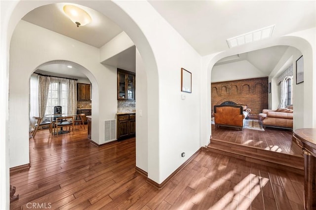 hall featuring baseboards, vaulted ceiling, hardwood / wood-style flooring, and visible vents