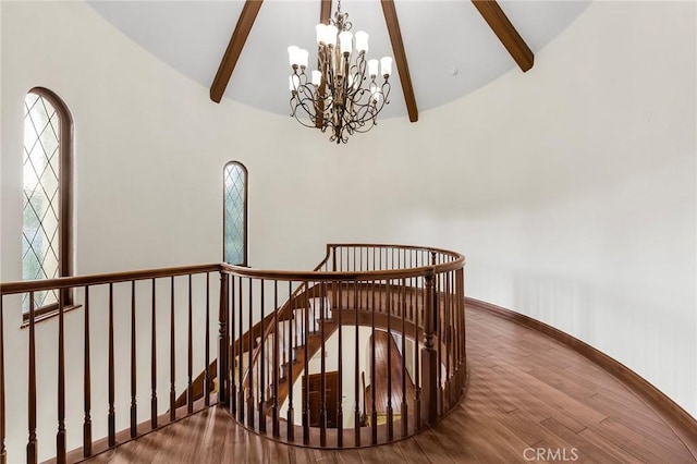 stairs featuring baseboards, a chandelier, lofted ceiling with beams, and wood finished floors