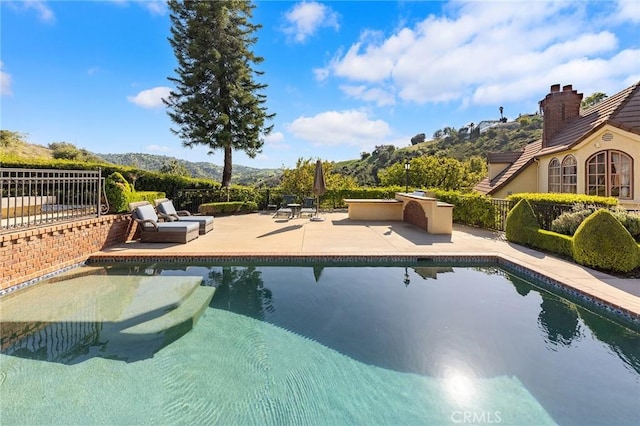 view of pool with fence, a fenced in pool, a patio, and a mountain view