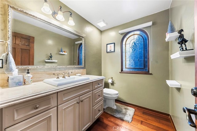 bathroom featuring vanity, baseboards, toilet, and wood finished floors