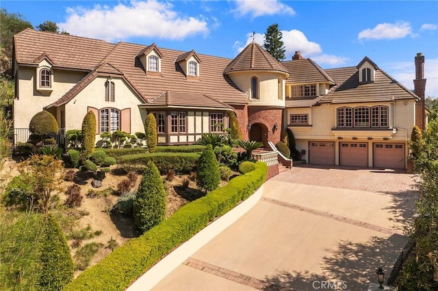 view of front of house featuring an attached garage, driveway, a chimney, and stucco siding