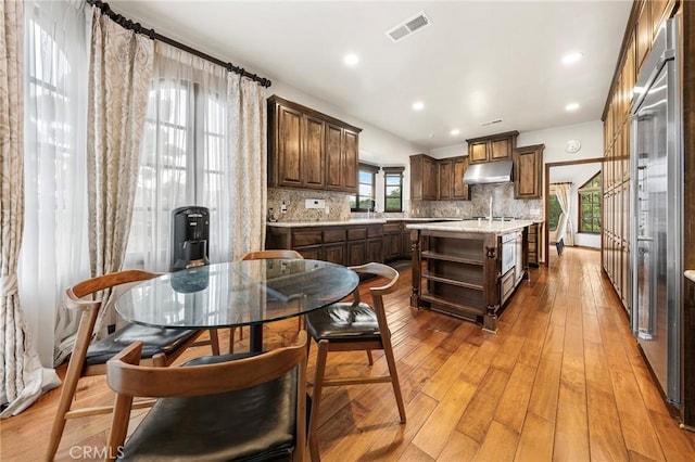 kitchen featuring a wealth of natural light, open shelves, under cabinet range hood, and visible vents