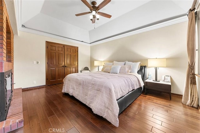 bedroom with a closet, baseboards, a tray ceiling, and dark wood-style floors