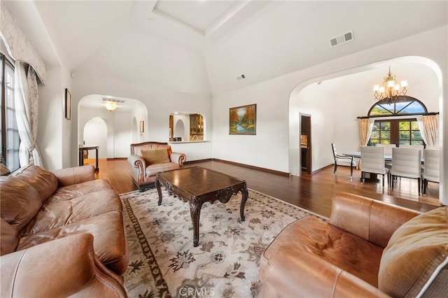 living area with arched walkways, an inviting chandelier, wood finished floors, and visible vents