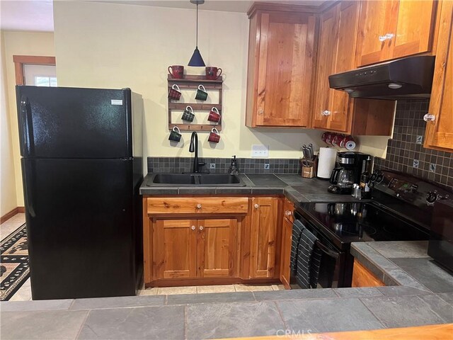 kitchen with a sink, brown cabinets, black appliances, and under cabinet range hood