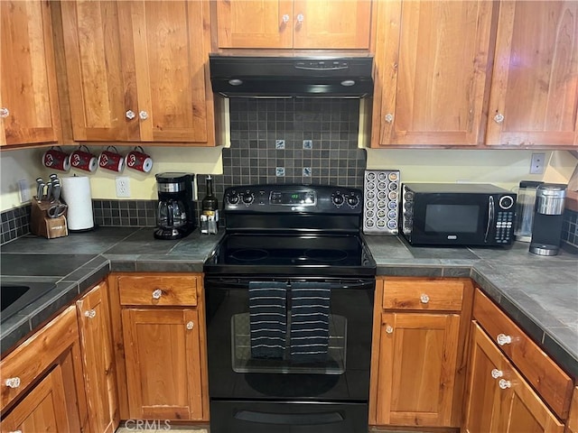 kitchen featuring decorative backsplash, range hood, black appliances, and brown cabinetry