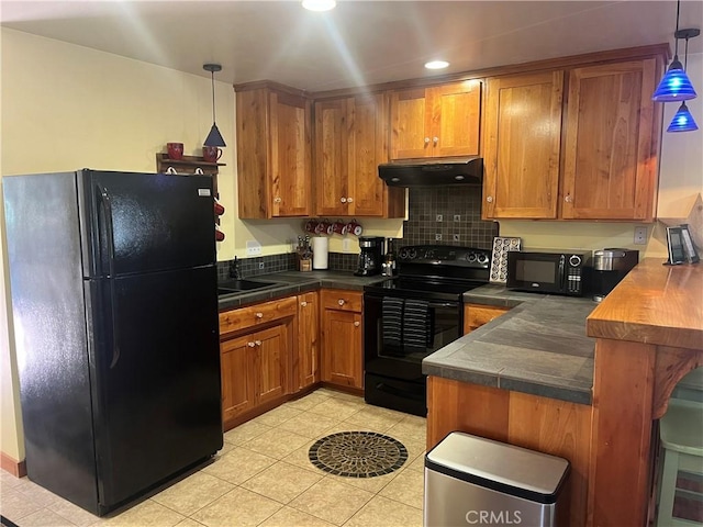 kitchen with light tile patterned floors, a peninsula, under cabinet range hood, brown cabinets, and black appliances