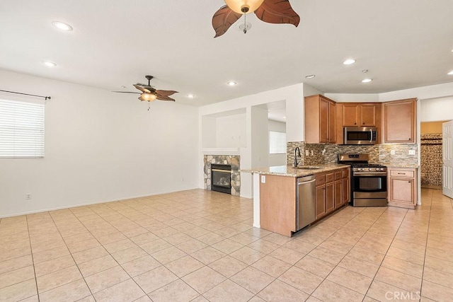 kitchen with appliances with stainless steel finishes, ceiling fan, a sink, and backsplash