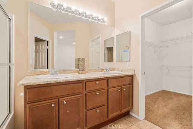 bathroom featuring a sink, an enclosed shower, a walk in closet, and double vanity