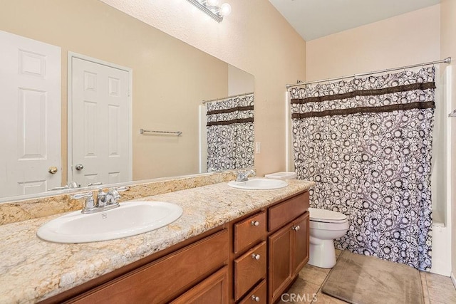 bathroom featuring toilet, double vanity, a sink, and tile patterned flooring