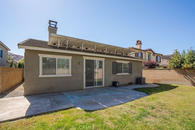 rear view of house featuring central AC unit, stucco siding, fence, and a lawn