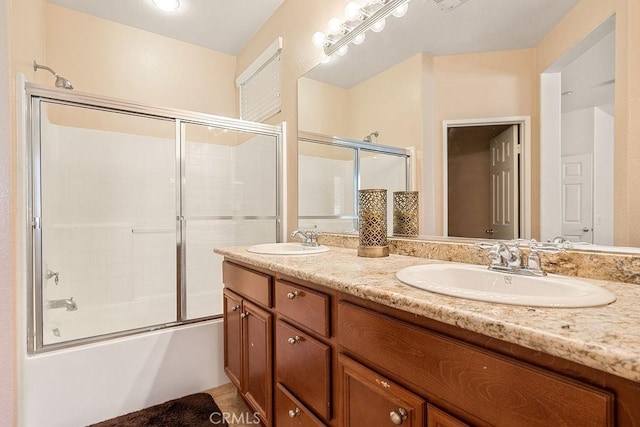 bathroom with shower / bath combination with glass door, double vanity, and a sink