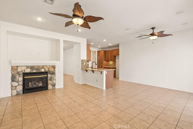 unfurnished living room with ceiling fan, a sink, light tile patterned floors, and recessed lighting