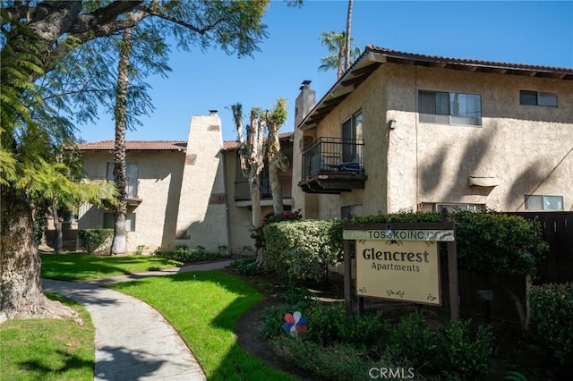 exterior space with a chimney, stucco siding, and a tiled roof