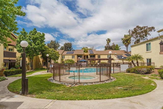 community pool with a lawn, fence, and a residential view