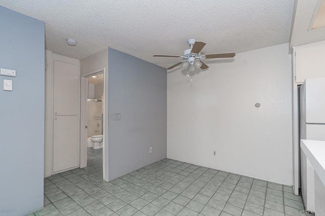 interior space featuring freestanding refrigerator, a textured ceiling, ceiling fan, and light tile patterned flooring