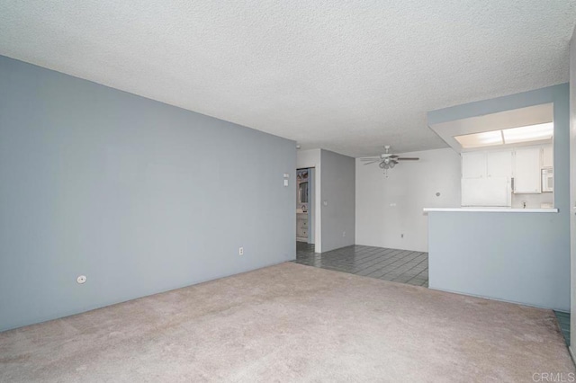 carpeted empty room featuring ceiling fan and a textured ceiling