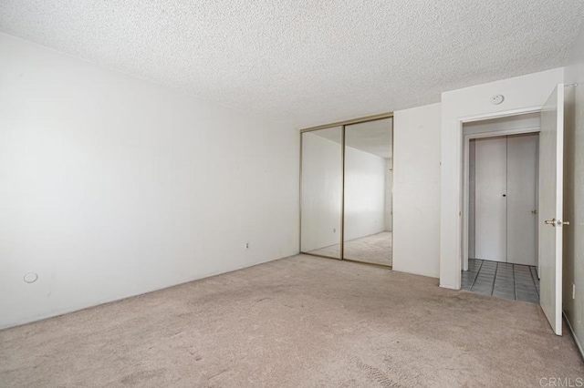 unfurnished bedroom with carpet floors, a textured ceiling, and a closet