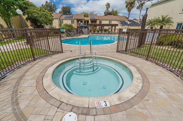 community pool featuring a hot tub and fence