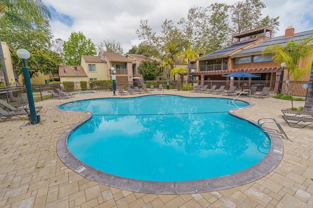 community pool with a patio area and fence