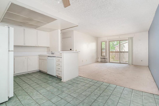 kitchen with a textured ceiling, light countertops, open floor plan, light carpet, and white appliances