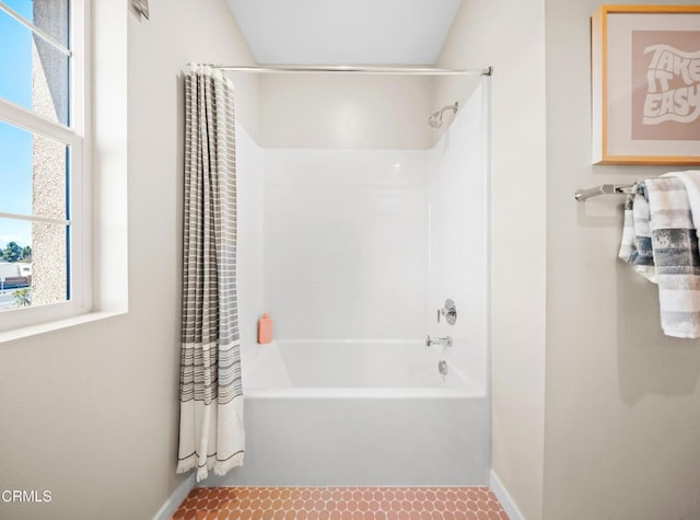 bathroom featuring shower / bath combination with curtain, baseboards, and a healthy amount of sunlight