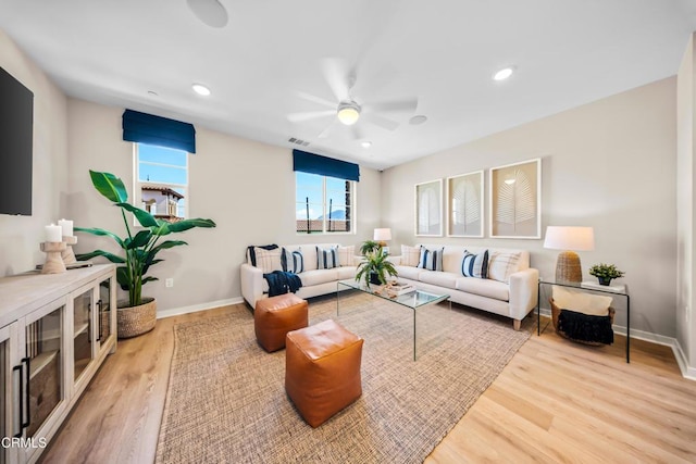 living room featuring visible vents, baseboards, wood finished floors, and ceiling fan