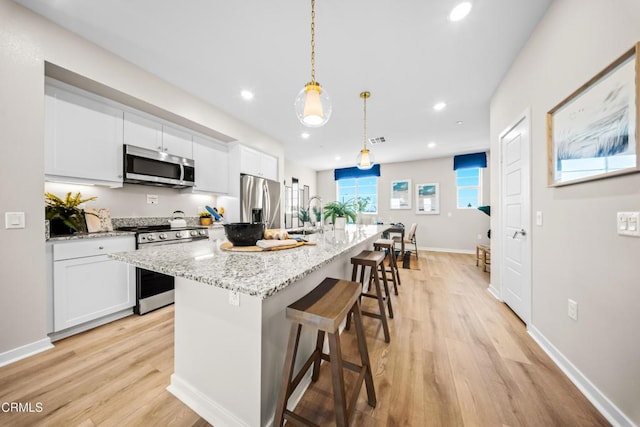 kitchen featuring light wood finished floors, a breakfast bar, recessed lighting, and stainless steel appliances