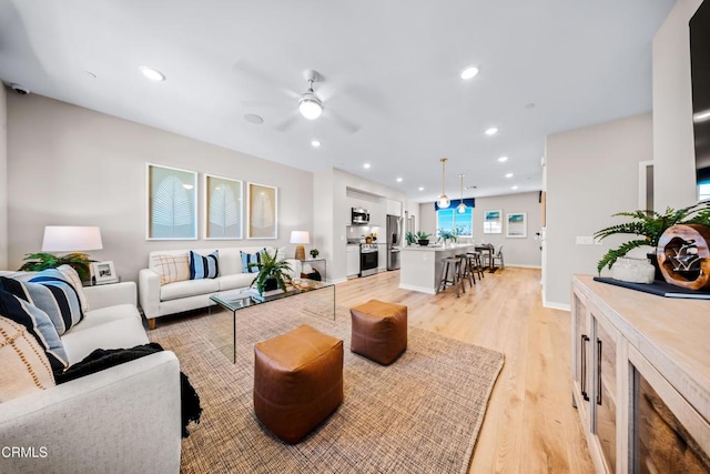 living area with ceiling fan, recessed lighting, light wood-style floors, and baseboards
