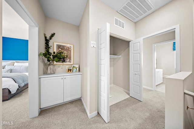 hallway featuring light carpet, baseboards, and visible vents