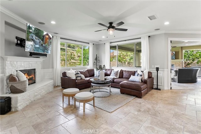 living area with stone tile floors, a stone fireplace, and ornamental molding