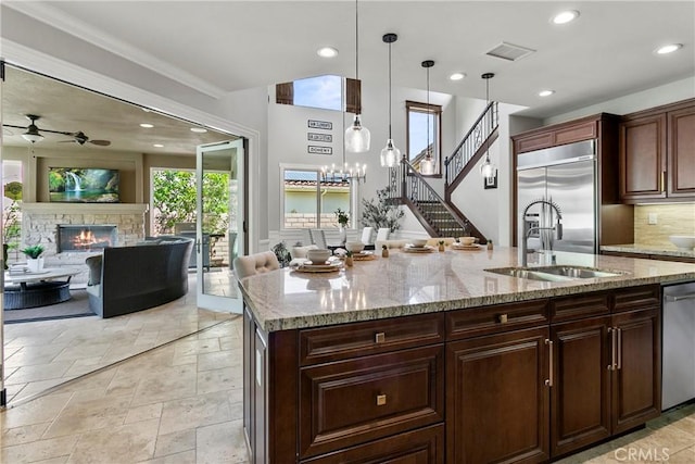 kitchen with appliances with stainless steel finishes, a ceiling fan, a stone fireplace, and recessed lighting