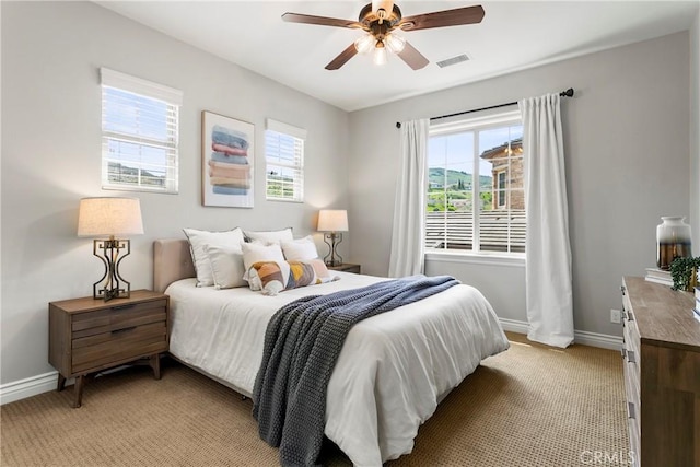 bedroom featuring baseboards, visible vents, a ceiling fan, and light colored carpet